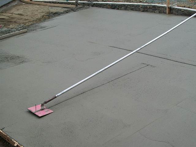 Photo of a concrete float being used to smooth the surface of the concrete driveway.
