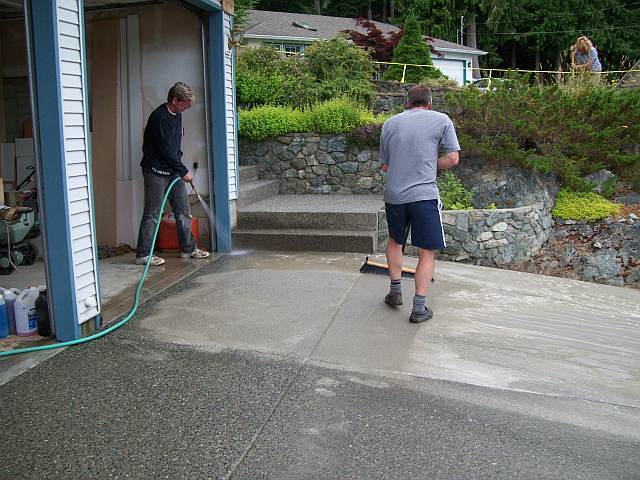 Photo of Dave sweeping away the wet surface of the concrete to expose the aggragate stones for the finish look of the driveway.